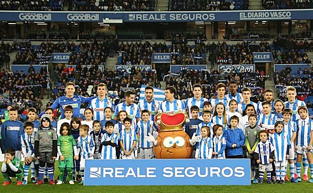 Los jugadores de la Real, con los niños y la mascota al inicio del choque. 