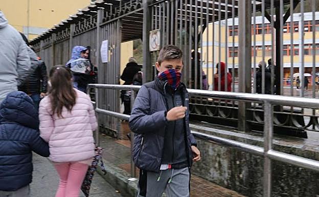 Niños que salen de clase y se protegen la nariz y la boca. 