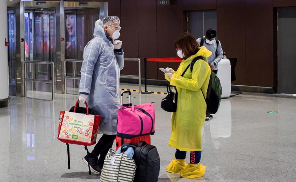 Dos viajeros portan ropa protectora en el aeropuerto internacional Daxing de Pekín, en China.