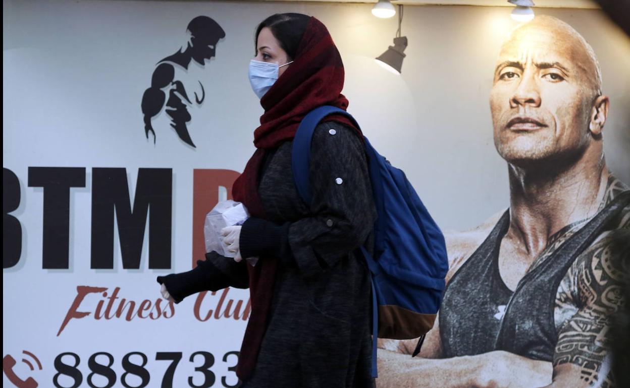 Una mujer pasea con mascarilla por las calles de Teherán.