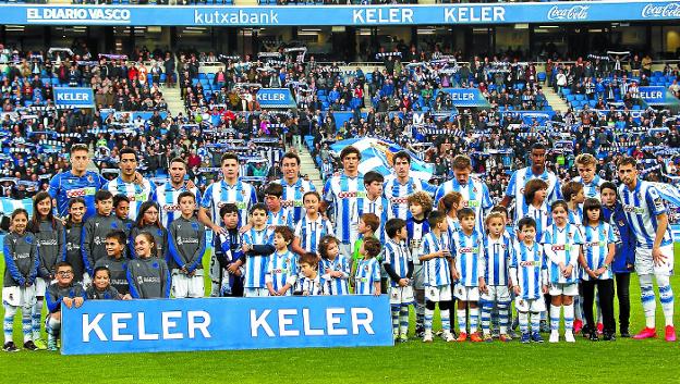 Los jugadores de la Real Sociedad posan con niños y niñas antes del inicio del partido.