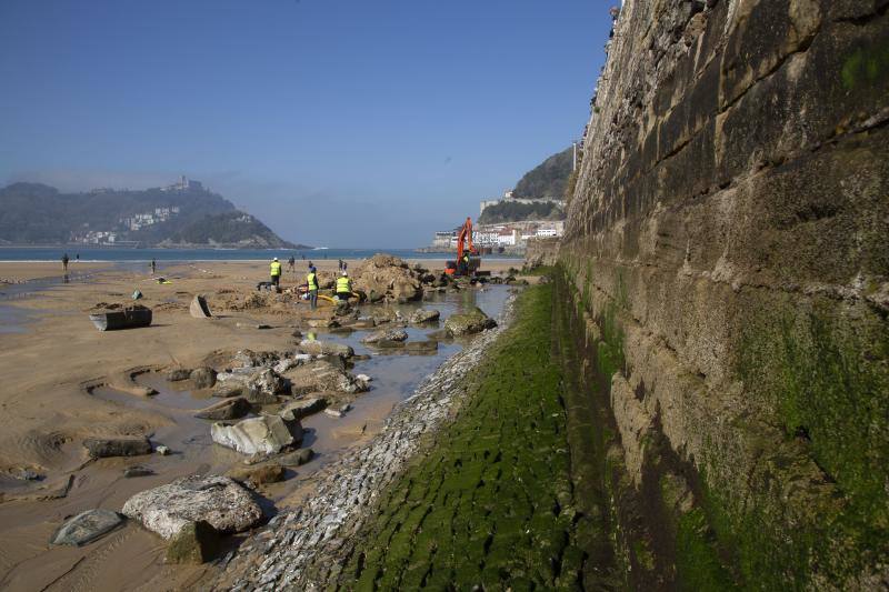 La playa de La Concha se ha convertido en la bajamar de este lunes por la mañana en un inesperado yacimiento arqueológico. La presencia de una pequeña excavadora retirando piedras y escombros junto al muro de costa a la altura del edificio consistorial ha suscitado una gran expectación entre los numerosos viandantes y turistas que han provechado el buen tiempo para dar un paseo. La máquina profundizaba en la arena en busca de los restos de un barco hundido del que hay constancia documental desde el siglo XVIII. 