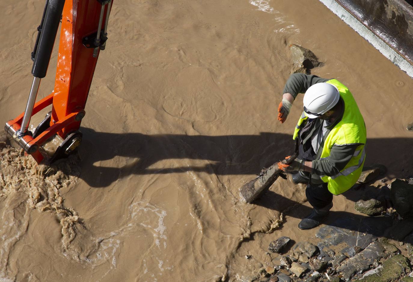 La playa de La Concha se ha convertido en la bajamar de este lunes por la mañana en un inesperado yacimiento arqueológico. La presencia de una pequeña excavadora retirando piedras y escombros junto al muro de costa a la altura del edificio consistorial ha suscitado una gran expectación entre los numerosos viandantes y turistas que han provechado el buen tiempo para dar un paseo. La máquina profundizaba en la arena en busca de los restos de un barco hundido del que hay constancia documental desde el siglo XVIII. 