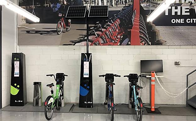 Varias bicicletas en sus anclajes y postes informativos con paneles solares.