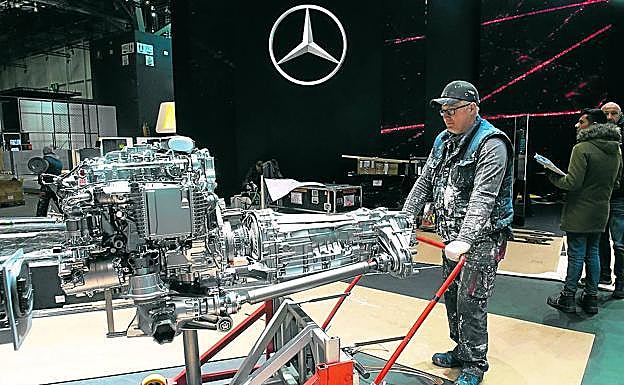 Un empleado retira un motor del stand de Mercedes en el Salón de Ginebra, que ha sido cancelado.