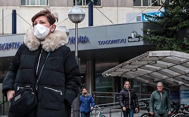 Una mujer se protege con una mascarilla en el exterior del Hospital Txagorritxu, donde se controla un posible foco de infección por coronavirus. 