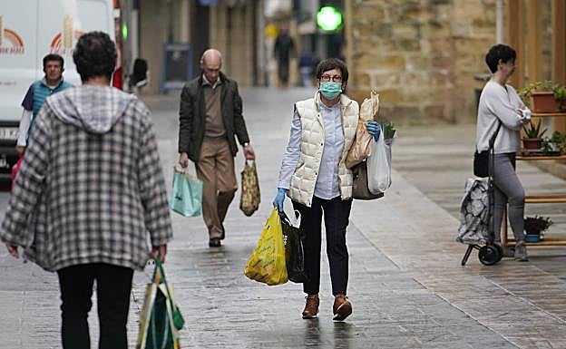 Una mujer protegida con una mascarilla y guantes carga con las bolsas de la compra ayer en Zarautz. 
