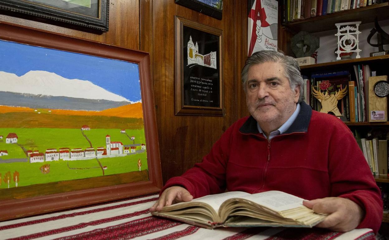 Eguiguren lee un libro en su casa junto a un óleo de su pueblo natal, Aizarna, que ha pintado en los últimos meses.