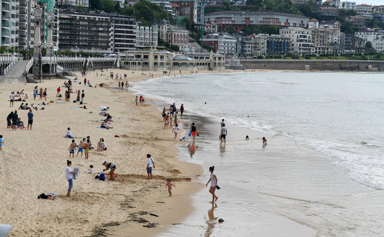Muchas familias con niños, ayer por la tarde, jugando en una playa de La Concha nublada. 