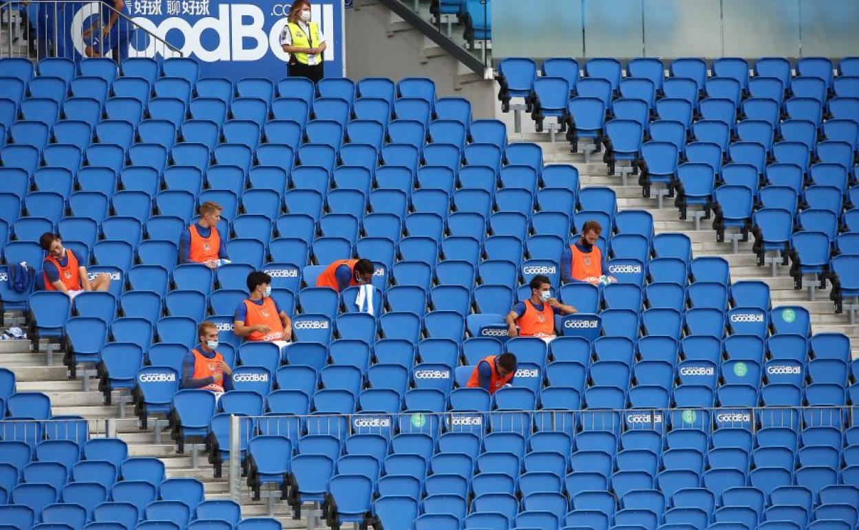 Los jugadores de la Real Sociedad sentados en la grada guardando la distancia de seguridad 