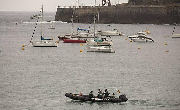 Imagen principal - La playa de Ondarreta con bandera roja, la bahía vacía de embarcaciones y bañistas desde Igeldo y la patrullera de la Guardia Civil durante las labores de búsqueda.