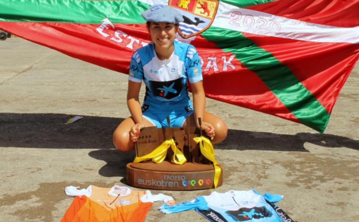 Nadeth Agirre sonríe con el trofeo liguero y los maillots de campeonas y el de mejor patrona. A su espalda, la bandera ganada en Zarautz. 