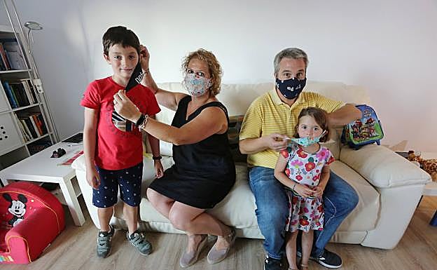 Tatiana e Iñigo colocan la mascarilla a sus hijos antes de acudir al cole. 