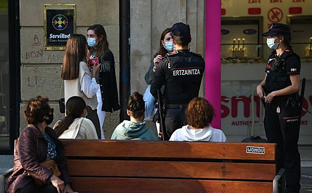 Imagen principal - La ertzaina invita a una mujer a colocarse adecuadamente la mascarilla, por encima de la nariz. 
