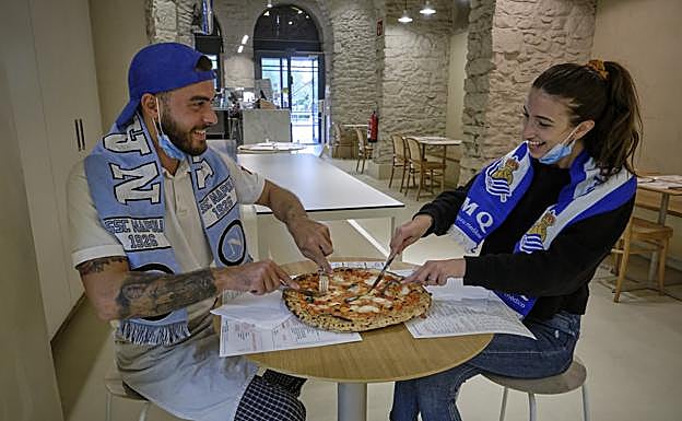 Vincenzo Angellotti, con la bufanda del Nápoles, y Alessia Tassan, de la Real, hincan el diente a una pizza.