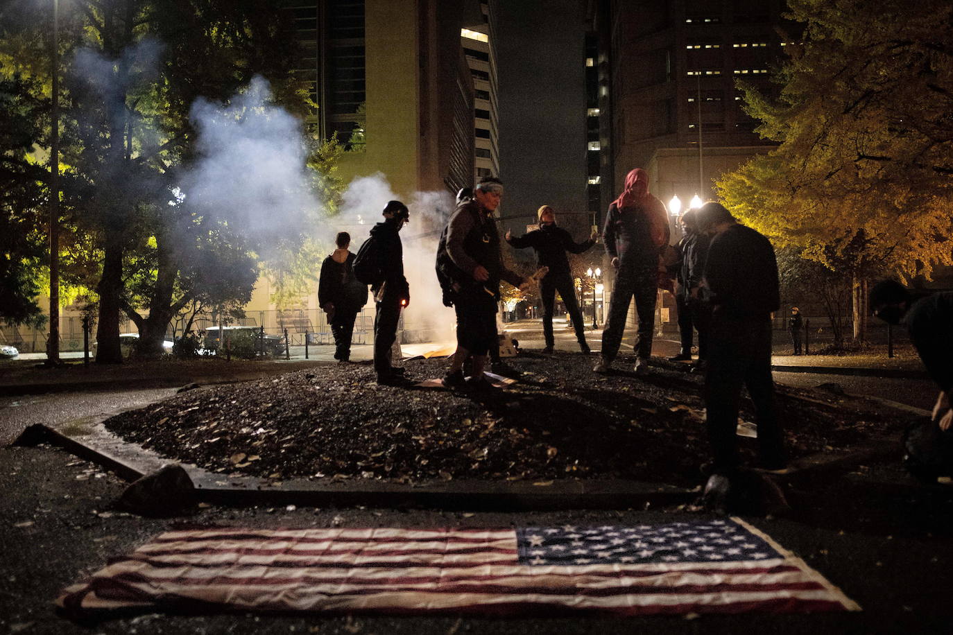 Varias personas, ante la bandera de EE UU (Portland).