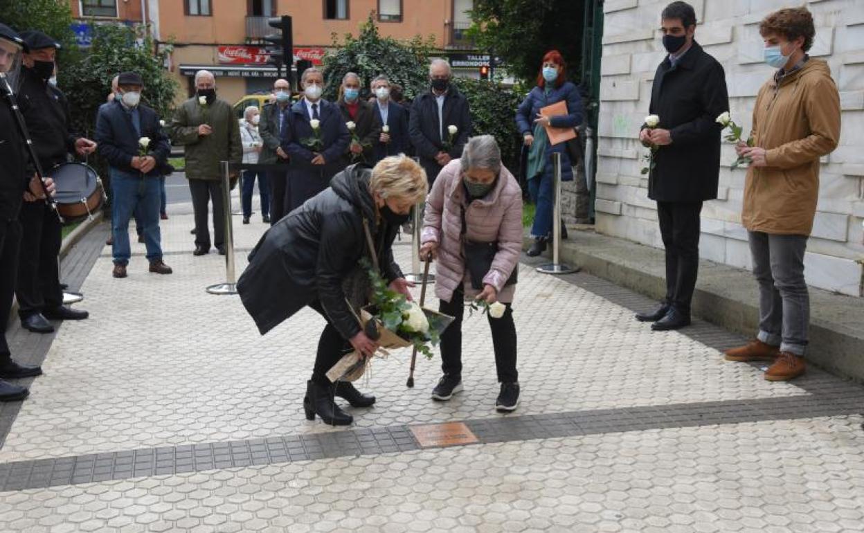 Dos mujeres depositan flores junto a la placa en memoria de Martín González. 