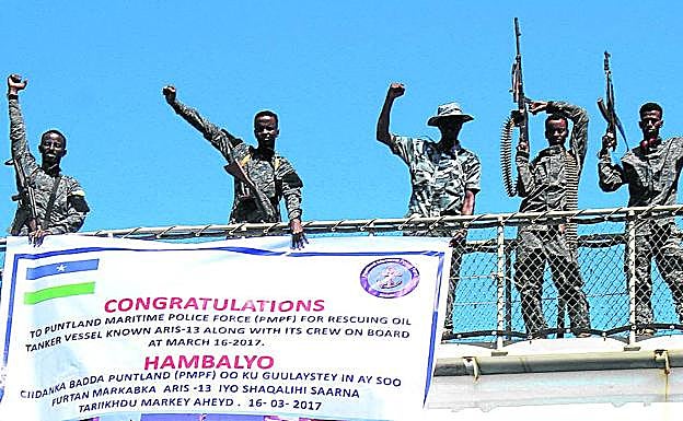 Imagen principal - Policías festejan encaramados a un tanque de petróleo un rescate marítimo. Abajo, una vendedera callejera de gasolina en Mogadishu y una mujer de de beber a un nño desnutrido.