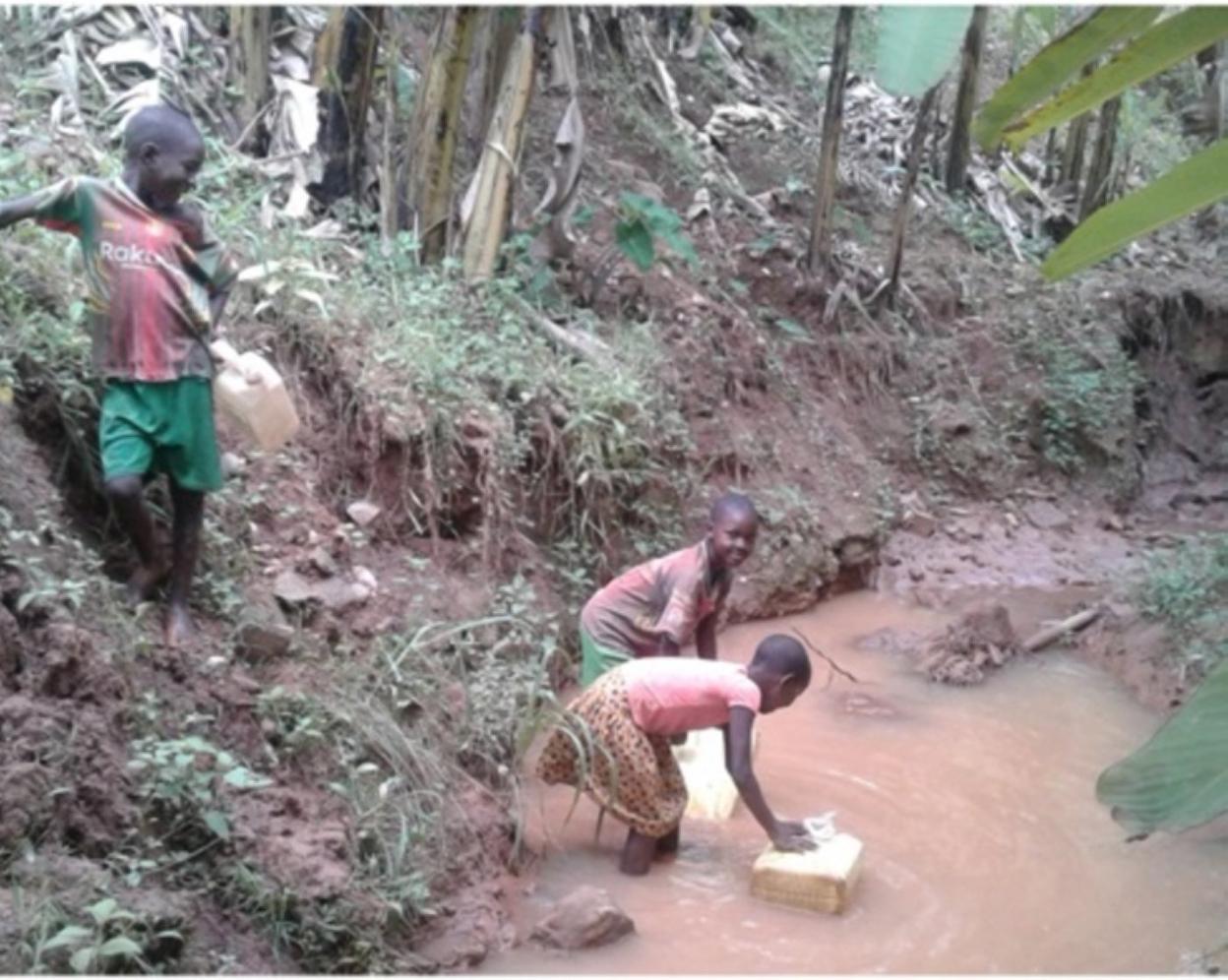 Dos niñas llenan sus bidones de agua en una poza en Kabuga. 
