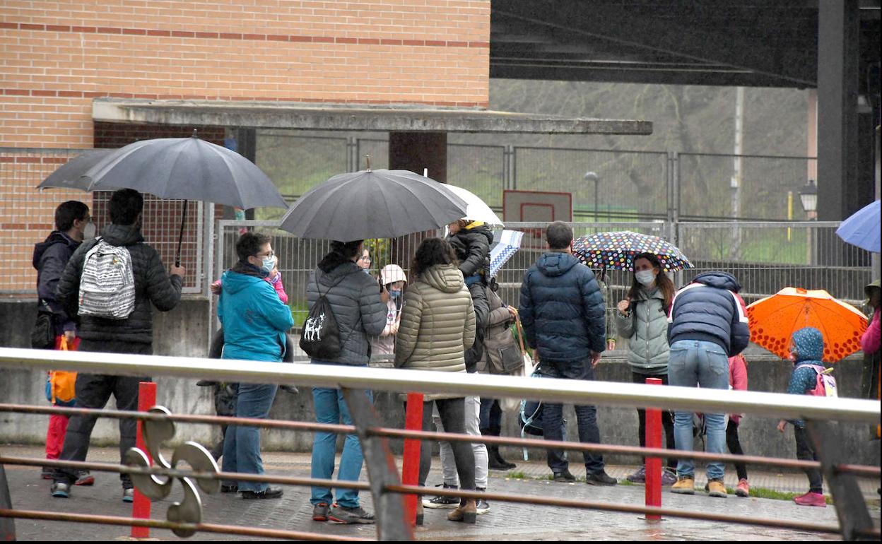 Varios padres y madres esperan a sus hijos a la salida de la escuela. 