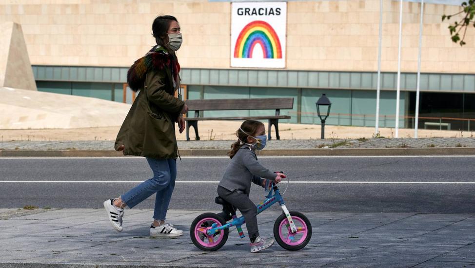 Una mujer pasea con su hija en Ávila tras permitirse las salidas de los niños por primera vez el 26 de abril, tras más de un mes confinados. 