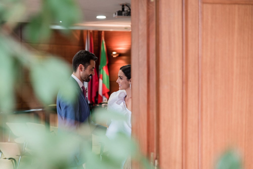 María y Jorge se casaron en Gorliz en una ceremonia íntima adaptada a las circunstancias. De largura 'mini' por encima de la rodilla, con corte asímetrico, volumen en la parte superior y lazadas laterales, la protagonista se ha convertido en una de las novias más impresionantes de las últimas semanas. El diseño lo ha firmado Fabio Encinar, uno de los diseñadores con sede en Madrid más de moda. En cuanto al peinado, otro de los elementos más destacados del estilismo, ha optado por un acertado moño bajo de bailarina súper pulido y tirante, con horquillas de Oui Novias