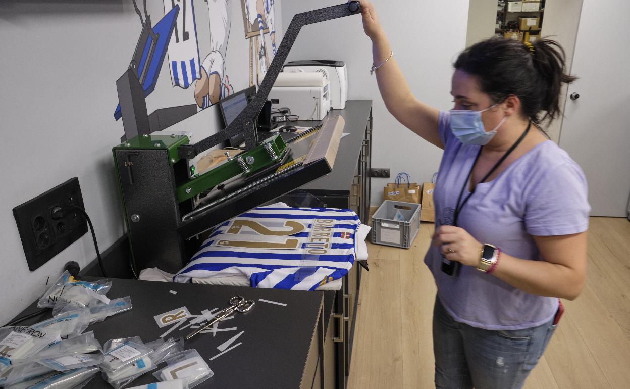 Una empleada de la tienda de la Real serigrafía el nombre en una de las camisetas especiales de la final .