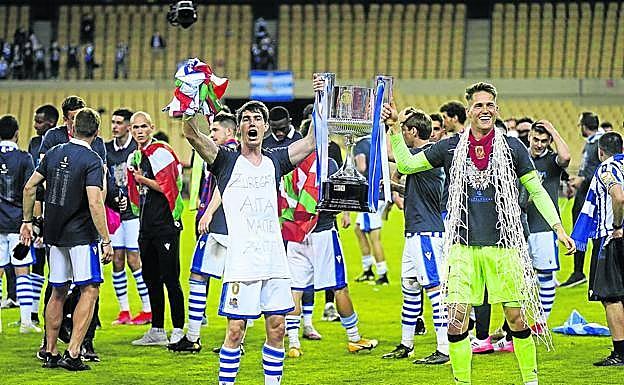 Aritz Elustondo y Álex Remiro, con la red de la portería de recuerdo, sujetan la Copa en las celebraciones tras el pitido final.