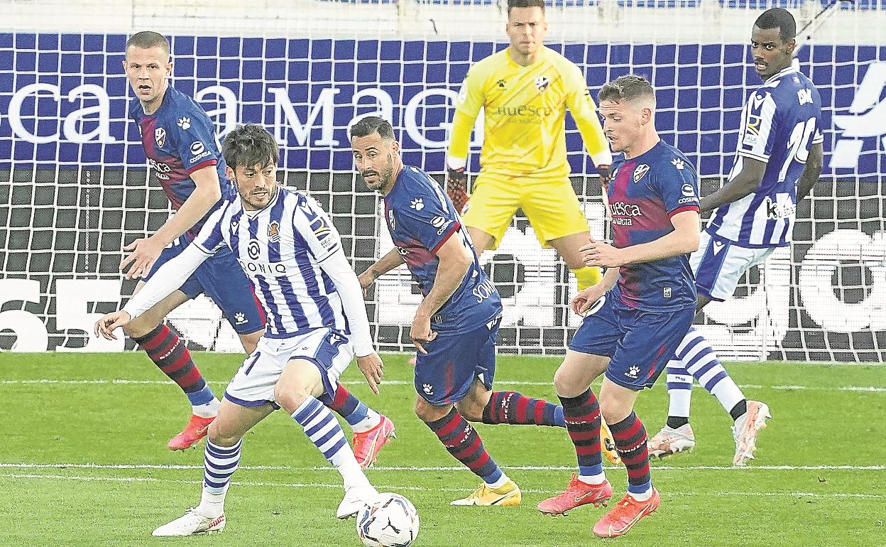 David Silva trata de girarse con el balón controlado ante la presión del futbolista oscense Sergio Gómez. 