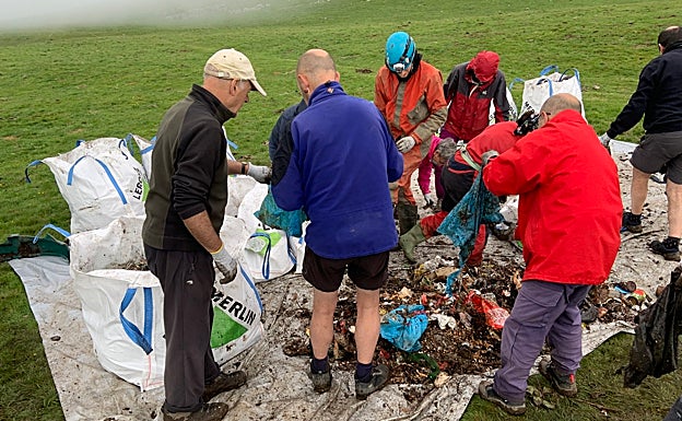 Varios participantes clasifican los residuos en el exterior de la sima .