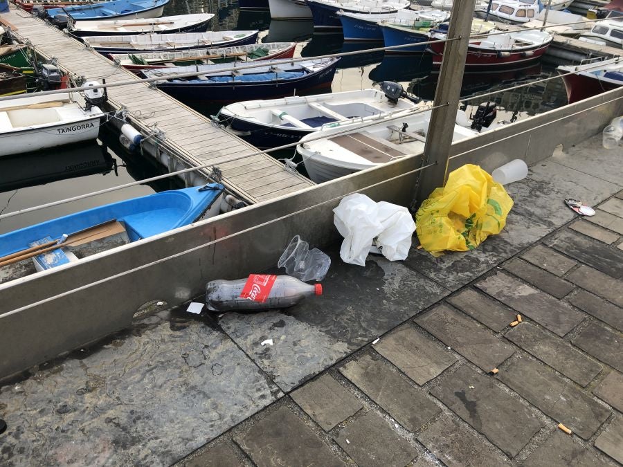 El puerto donostiarra ha amanecido cubierto de restos de plásticos y cristales después de una noche de botellón