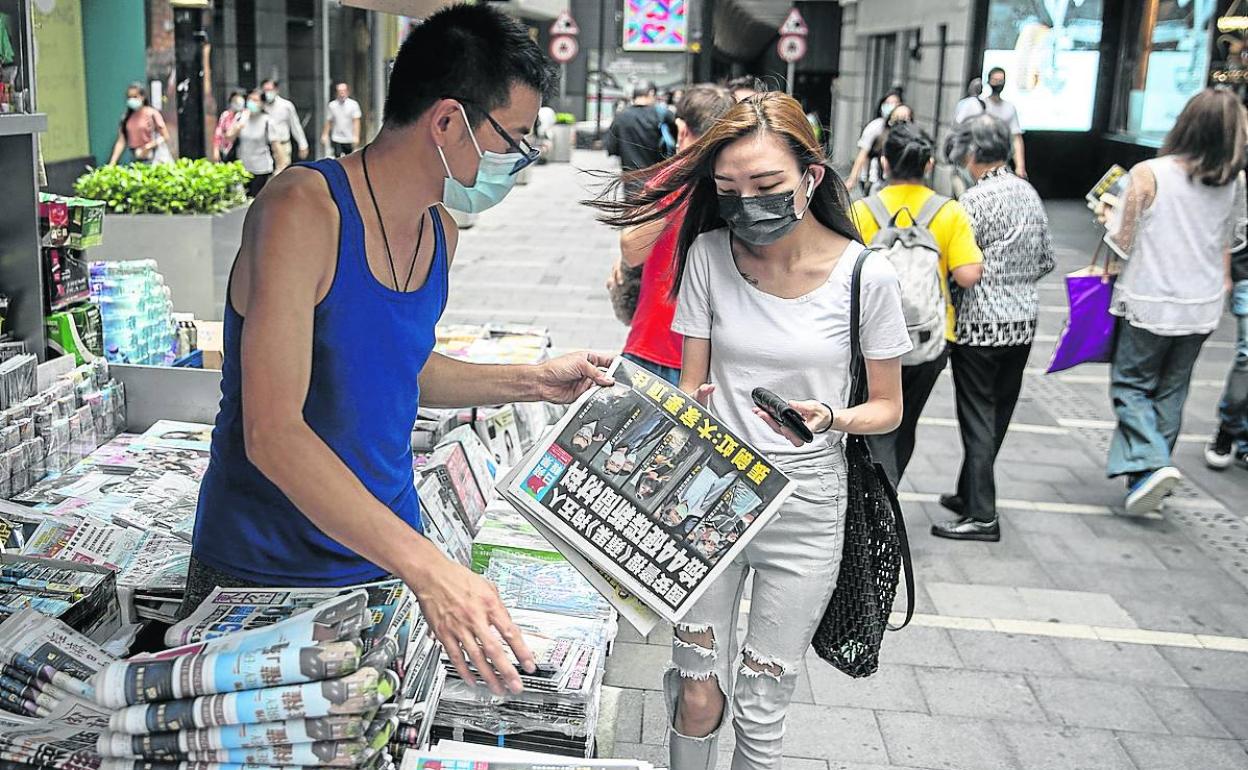 Una joven compra un ejemplar del 'Apple Daily' en un quiosco de Hong Kong. 
