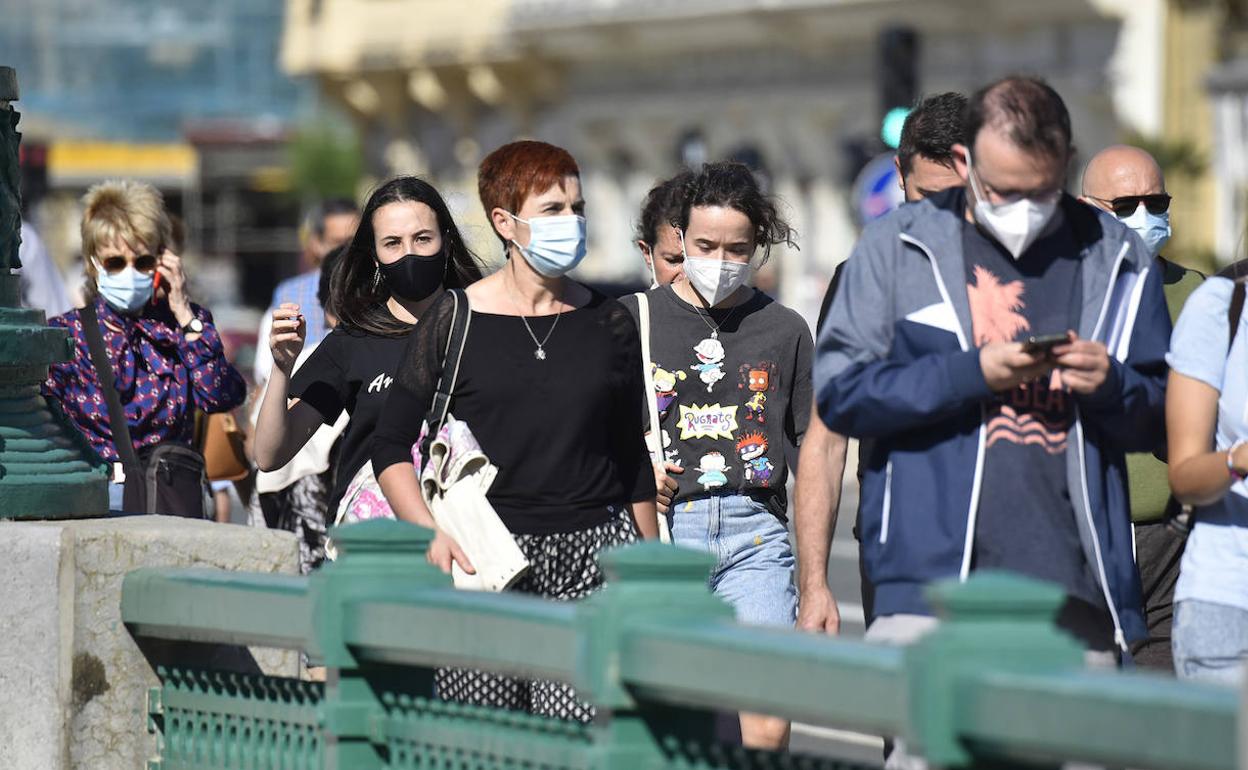 Varias personas pasean con mascarilla por Donostia pese a que el protector no es obligatorio al aire libre si se mantiene distancia
