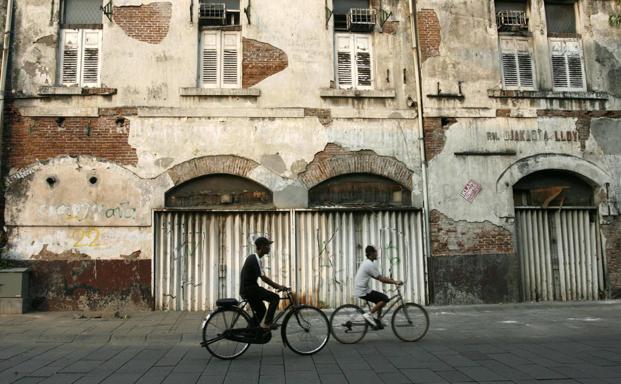 Dos Jóvenes circulan en bicicleta por una calle de la zona antigua de Yakarta. 