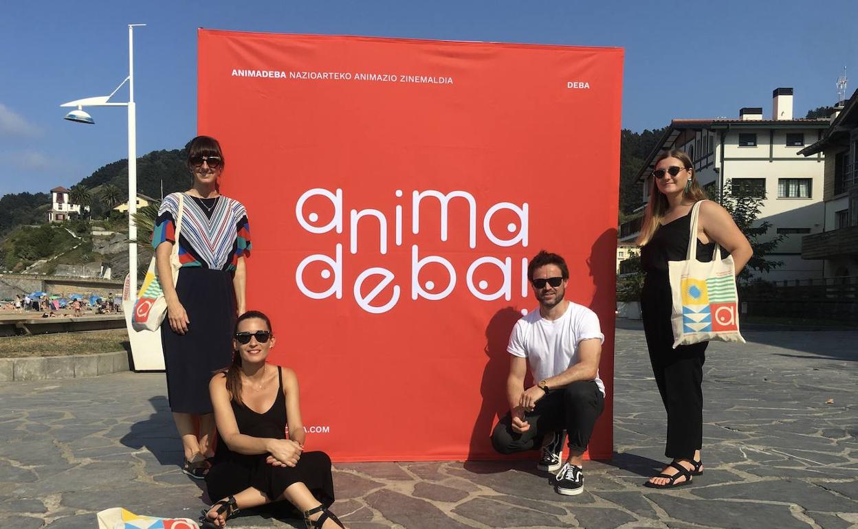 Los organizadores Ane Ibarzabal, Ainara Castro, Aitor Oñederra y Nere Oria posan junto al cartel en Deba. 