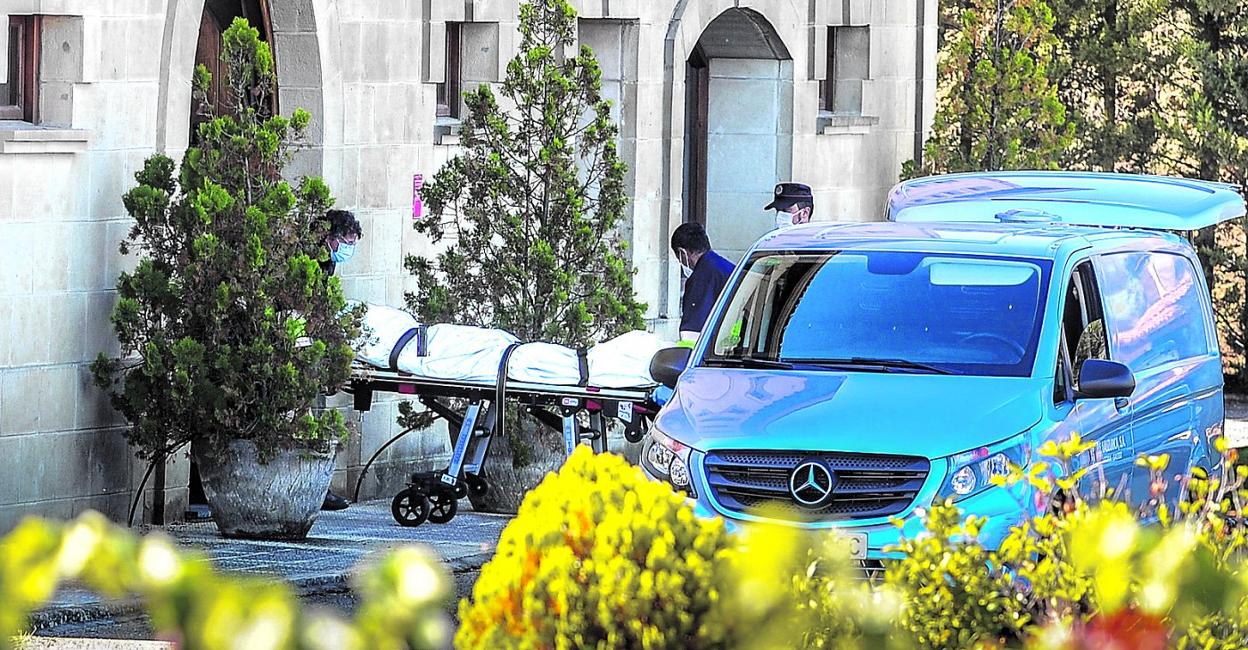 Operarios de la funeraria sacan el cadáver del fallecido. 