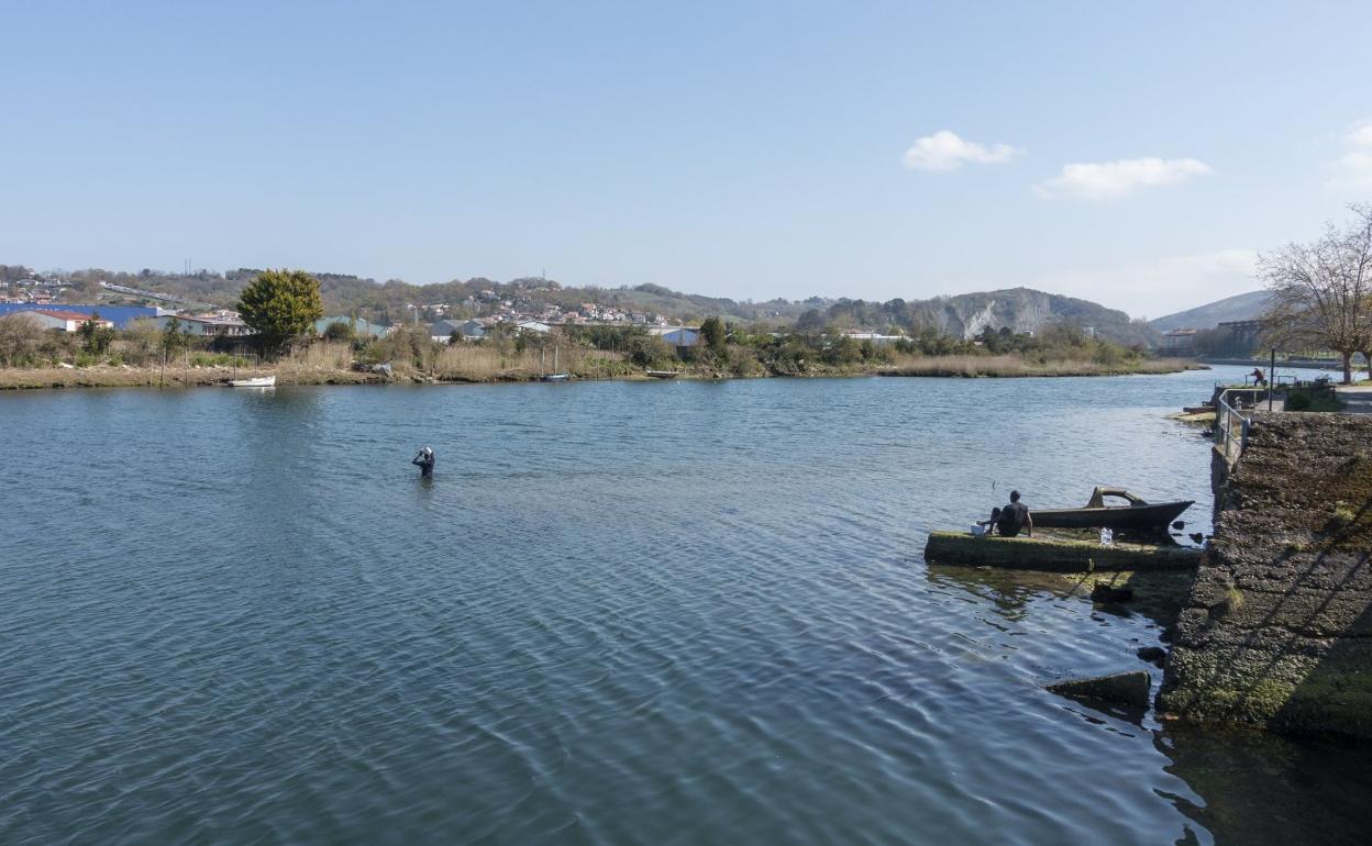 Un migrante cruza el río Bidasoa, mientras otro le observa desde la orilla. 