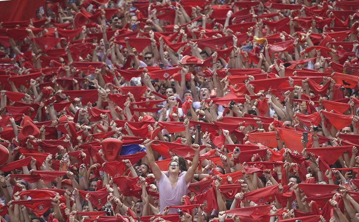 Jóvenes con el pañuelico rojo en alto durante el chupinazo de 2019