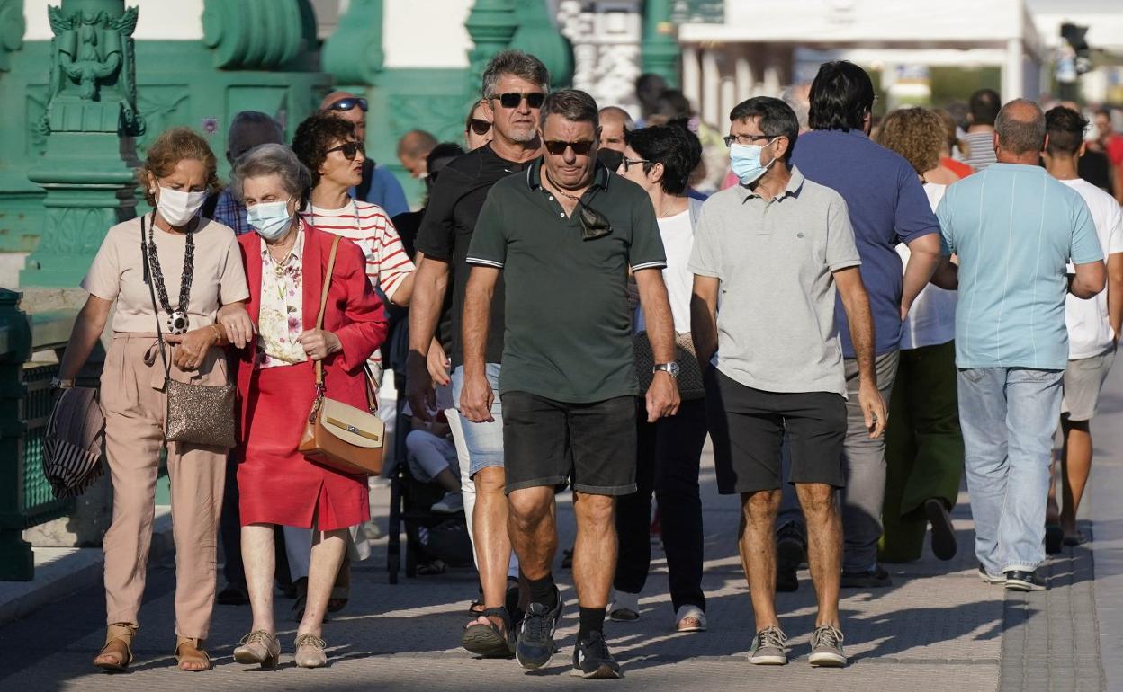 Paseantes, con y sin mascarilla, atraviesan el puente de la Zurriola en Donostia. 