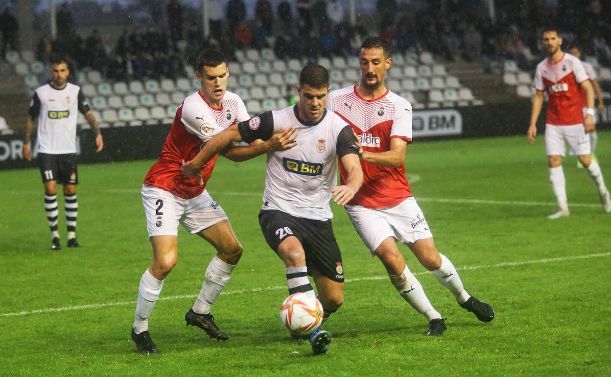 Un jugador del Real Unión disputa el balón junto a otros dos del Racing. 
