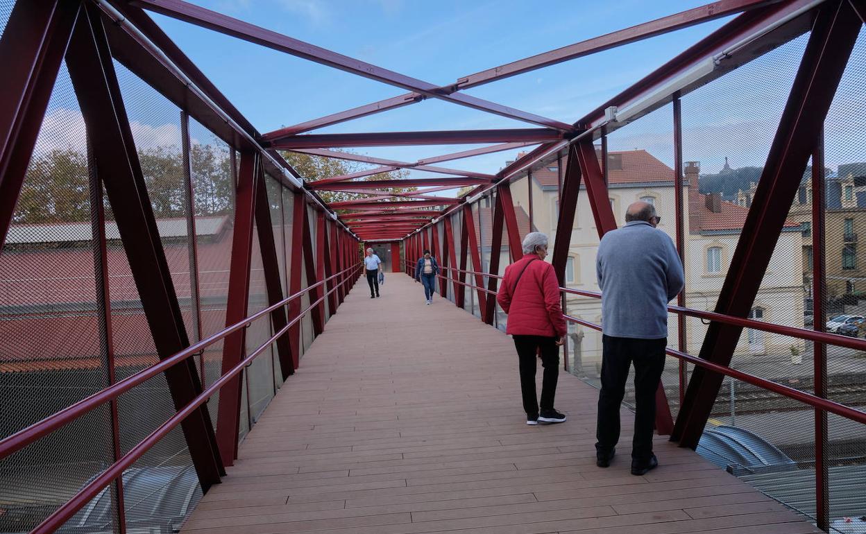 Unos viandantes cruzan la pasarela peatonal sobre la Estación del Norte.