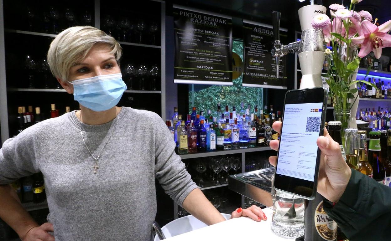 Un cliente enseña su pasaporte Covid a la camarera de un bar. 