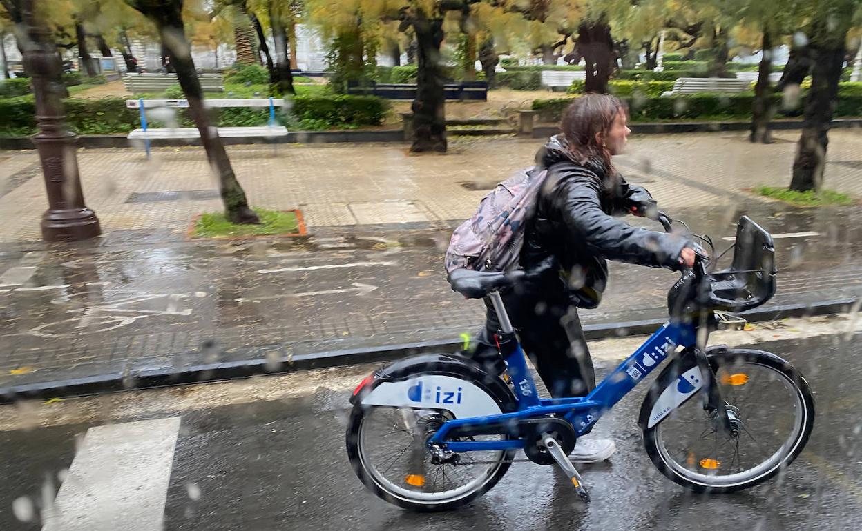 Una chica empapada con una bici ayer jueves en San Sebastián.