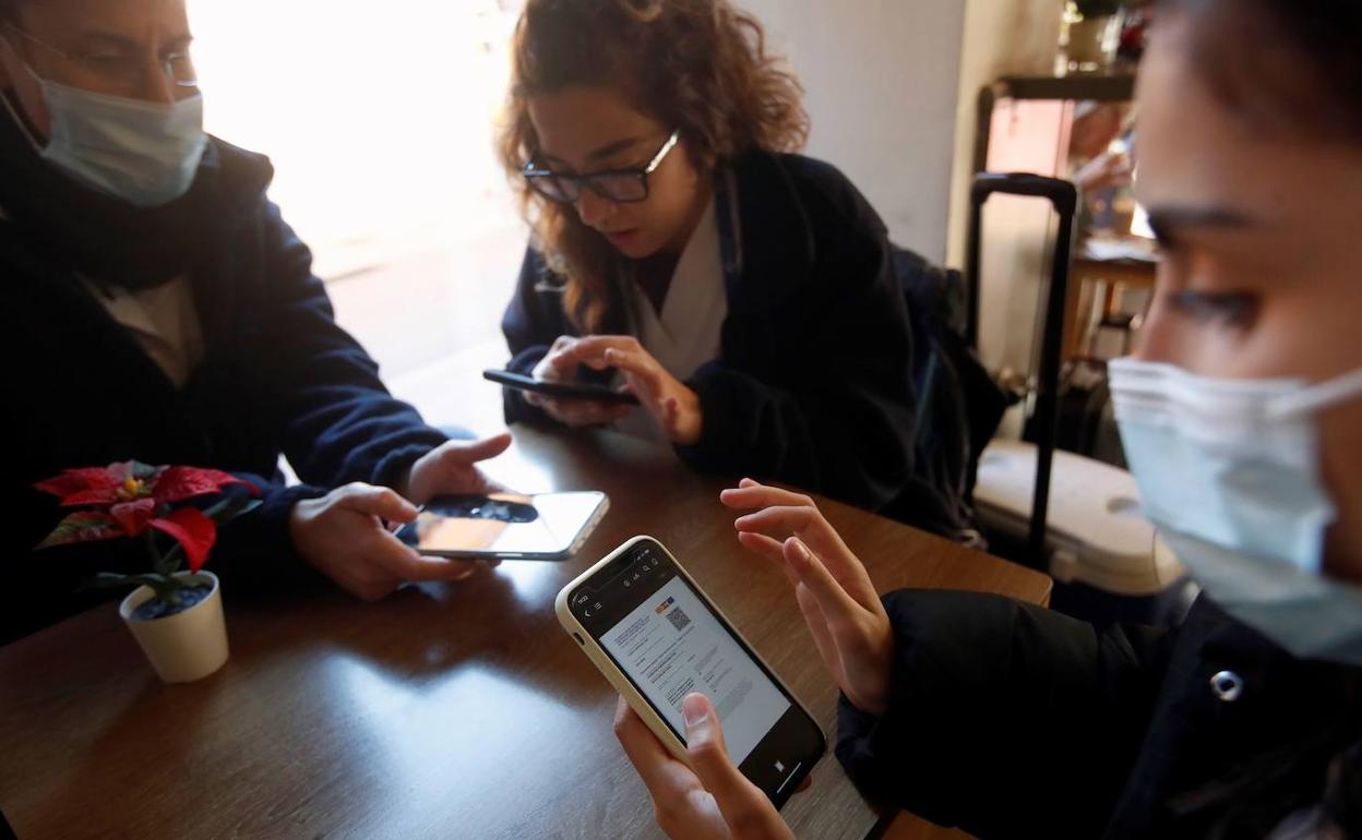 Tres jóvenes con su pasaporte descargado en el móvil.