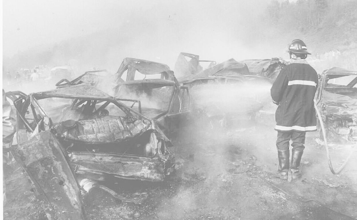 Un bombero sofoca el fuego originado entre los vehículos que quedaron totalmente calcinados,