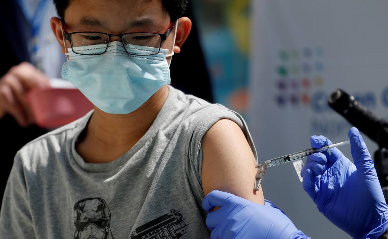 Sanitarios vacunan a un menor de edad con Pfizer.