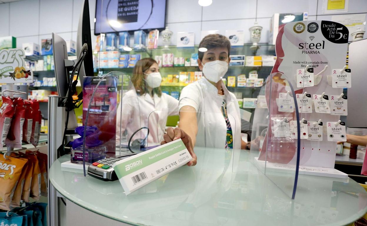 Una farmacéutica muestra uno de los test de antígenos, cuya demanda sigue disparada. 