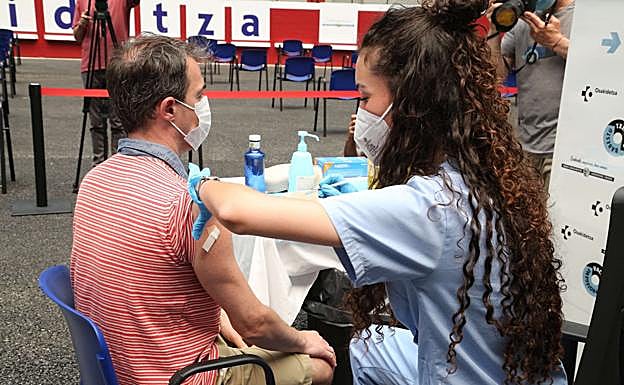 Un hombre de mediana edad recibe una de las primeras vacunas. 