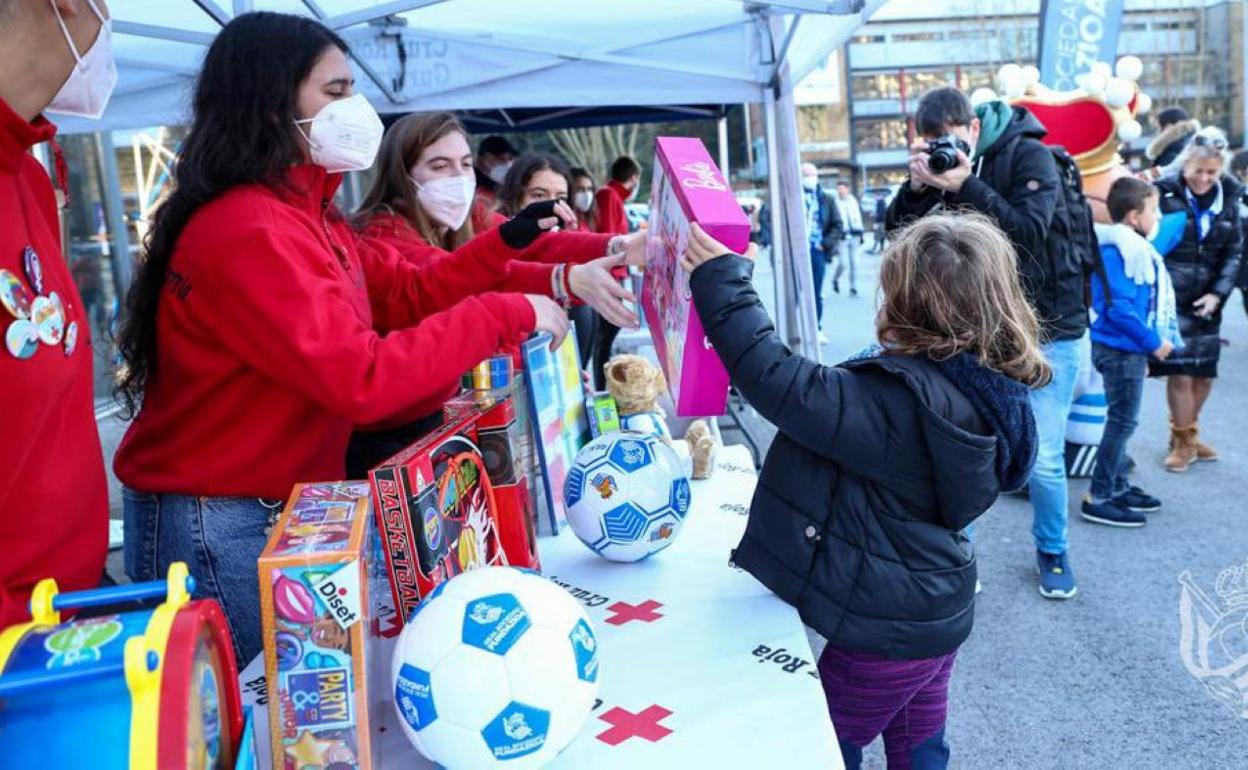 Una niá entrega un juguete a los voluntarios de la Cruz Roja en Anoeta. 
