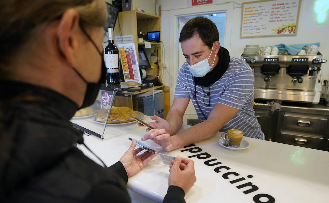 Un hostelero compruebla el pasaporte Covid de una clienta.